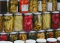 Vibrant display of pickled vegetables in jars at a traditional Turkish market.