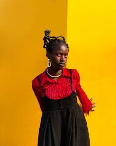 A bold fashion statement with a woman wearing red and black against a vibrant yellow background, showcasing unique style.