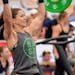 Focused female athlete lifting weights at an outdoor competition showcasing strength and determination.