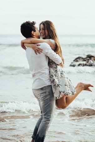 Happy couple in love embracing on a sandy beach by the ocean.