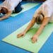 Senior adults stretching on yoga mats inside a gym, promoting health and fitness.