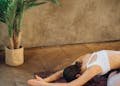 Woman in child's pose on yoga mat with candles and plant, creating a serene indoor setting.