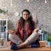 Young woman meditating with headphones in a modern office setting, practicing mindfulness.